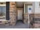 Inviting covered entryway and porch is framed by stone pillars and complementary siding at 5037 N Quemoy St, Aurora, CO 80019