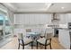 Bright kitchen with a round glass table, white cabinets, stainless appliances, and ample natural light at 5037 N Quemoy St, Aurora, CO 80019