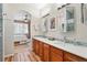 Bathroom featuring a long wooden vanity with double sinks, mirrors, modern lighting and access to the primary bedroom at 11230 Osage Cir # B, Northglenn, CO 80234