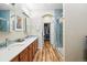 Bathroom with double sinks, wooden cabinets, large mirrors, blue accents, and a shower stall at 11230 Osage Cir # B, Northglenn, CO 80234