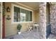 Cozy front porch with a small table and chairs, framed by stone columns and a large window at 11230 Osage Cir # B, Northglenn, CO 80234