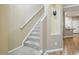 Carpeted staircase with white railing next to a kitchen with light wood floors at 11230 Osage Cir # B, Northglenn, CO 80234