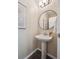 Half bath featuring a pedestal sink, round mirror, and decorative artwork at 5193 E 119Th Way, Thornton, CO 80233