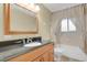 Bathroom with a wooden vanity, black countertop, and bathtub with shower at 7784 Lewis St, Arvada, CO 80005