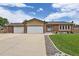 The house has a well-manicured front yard and a long driveway leading to a two-car garage at 7784 Lewis St, Arvada, CO 80005