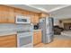 Bright kitchen features white appliances, light wood cabinetry, and adjacent living room at 7784 Lewis St, Arvada, CO 80005