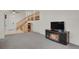 Spacious living room with stairs, fireplace, and a wall mounted television and wood and glass cabinet at 7784 Lewis St, Arvada, CO 80005