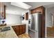 Well-lit kitchen featuring stainless steel appliances, granite countertops, dark wood cabinets, and a wall-mounted TV at 246 S Newark Cir, Aurora, CO 80012