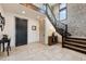 Bright foyer with stone accent wall, staircase with iron railing, and neutral tile flooring at 5623 Raintree Dr, Parker, CO 80134