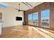 Living room with hardwood floors, brick accent wall, and large windows at 4258 Tennyson St # 104, Denver, CO 80212