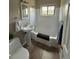 Bright bathroom featuring a pedestal sink, tub, and window for natural light, creating a clean and functional space at 1237 Tamarac St, Denver, CO 80220