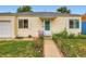 Charming yellow home with a well-manicured lawn and flower-lined walkway leading to a bright green front door at 1237 Tamarac St, Denver, CO 80220