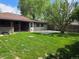 Spacious backyard featuring a patio area, lush lawn, mature trees, and privacy fence at 2285 Ironton St, Aurora, CO 80010