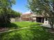 Well-maintained backyard with a lush lawn, mature trees, and a covered patio with a hot tub at 2285 Ironton St, Aurora, CO 80010