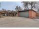 A detached garage with a gray door and brick siding stands on a concrete pad and offers secure parking and storage at 2285 Ironton St, Aurora, CO 80010