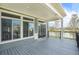Covered back patio with gray wood flooring, black metal railing, and large windows to the home's interior at 4873 Cathay Ct, Denver, CO 80249