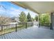 Covered back deck with black metal railing and view of lawn, trees, and neighboring home at 4873 Cathay Ct, Denver, CO 80249