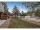 View of the grassy, fenced backyard with a mulched area and access to the wooden deck at 7506 Chipmunk Pl, Littleton, CO 80125