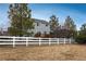View of the grassy backyard enclosed by a white fence, with a wooden deck adding charm at 7506 Chipmunk Pl, Littleton, CO 80125
