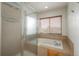 Bright bathroom features a bathtub with tile surround, glass enclosed shower, and window at 7506 Chipmunk Pl, Littleton, CO 80125
