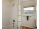 White-tiled shower with a colorful curtain, paired with a single window and wood-look vinyl flooring at 7506 Chipmunk Pl, Littleton, CO 80125