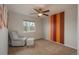 Bedroom with carpet, ceiling fan and accent wall with chair and ottoman by the window at 7506 Chipmunk Pl, Littleton, CO 80125