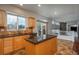 Well-lit kitchen with wooden cabinets, tile backsplash, and an island with a dark countertop at 7506 Chipmunk Pl, Littleton, CO 80125