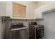 Modern laundry room with stainless steel LG washer and dryer set beneath wooden shelving and white cabinets at 7506 Chipmunk Pl, Littleton, CO 80125