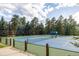 An outdoor tennis court surrounded by lush trees, providing a scenic and active recreational amenity at 222 Greystone Rd, Evergreen, CO 80439