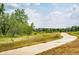 Scenic view of a paved walking path through a grassy field with trees and community homes in the distance at 22405 E Plymouth Cir, Aurora, CO 80016