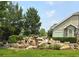 Beautiful water feature with multiple tiers of rocks and lush greenery in a well-maintained front yard at 22405 E Plymouth Cir, Aurora, CO 80016