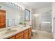 Bathroom featuring double sink vanity with wood cabinets, shower with glass door, and natural light at 831 W Kettle Ave, Littleton, CO 80120