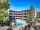 Apartment complex featuring a swimming pool and exterior staircases surrounded by mature trees at 33 N Corona St # 205, Denver, CO 80218
