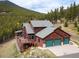 An exterior view of the home situated amongst the trees with a large garage at 76 Raven Ridge Rd, Idaho Springs, CO 80452