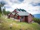 An exterior view of the home situated amongst the trees with solar panels at 76 Raven Ridge Rd, Idaho Springs, CO 80452
