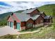An exterior view of the home situated amongst the trees with a large garage at 76 Raven Ridge Rd, Idaho Springs, CO 80452