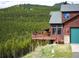 Mountain home featuring a deck with forest views, stone accents, and an attached garage at 76 Raven Ridge Rd, Idaho Springs, CO 80452