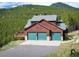A mountain home with a three-car garage and a large deck is nestled in a forest setting at 76 Raven Ridge Rd, Idaho Springs, CO 80452