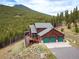 A mountain home with a large deck and a three-car garage is nestled in a forest setting at 76 Raven Ridge Rd, Idaho Springs, CO 80452