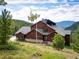 Beautiful exterior view of a mountain home featuring rustic wood siding and stunning views of the forest at 76 Raven Ridge Rd, Idaho Springs, CO 80452