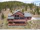An exterior view of the home situated amongst the trees with a deck at 76 Raven Ridge Rd, Idaho Springs, CO 80452