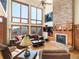 Cozy living room with stone fireplace, high windows with mountain views, and hardwood floors at 76 Raven Ridge Rd, Idaho Springs, CO 80452