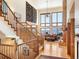 Open-concept living area with hardwood floors, a stone fireplace, large windows, and an adjacent staircase at 76 Raven Ridge Rd, Idaho Springs, CO 80452