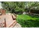 Wooden deck with built-in bench overlooks a lush, well-maintained backyard with mature landscaping and stone accents at 2141 Weatherstone Cir, Highlands Ranch, CO 80126
