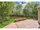 Landscaped backyard with mature trees, a wooden fence, and a wooden deck at 2141 Weatherstone Cir, Highlands Ranch, CO 80126