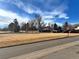 Open green space with mature trees, cars parked and distant buildings at 12423 E Louisiana Ave, Aurora, CO 80012