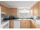 Kitchen with light wood cabinets, white appliances, and a double sink at 12423 E Louisiana Ave, Aurora, CO 80012