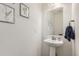 Charming powder room featuring pedestal sink, decorative mirror, and modern fixtures at 6233 N Liverpool St, Aurora, CO 80019