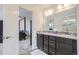 Bathroom featuring double vanity, dark cabinets and door open to primary bedroom at 6233 N Liverpool St, Aurora, CO 80019