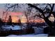 Panoramic view of the vibrant sunset over the neighborhood rooftops with snow-covered landscapes and silhouetted trees at 2311 E 96Th Way, Thornton, CO 80229